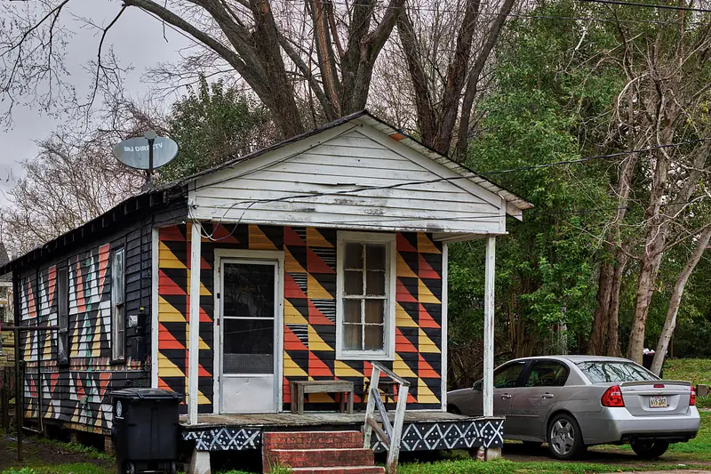 A small shotgun house painted in a bold geometric pattern in Baton Rouge