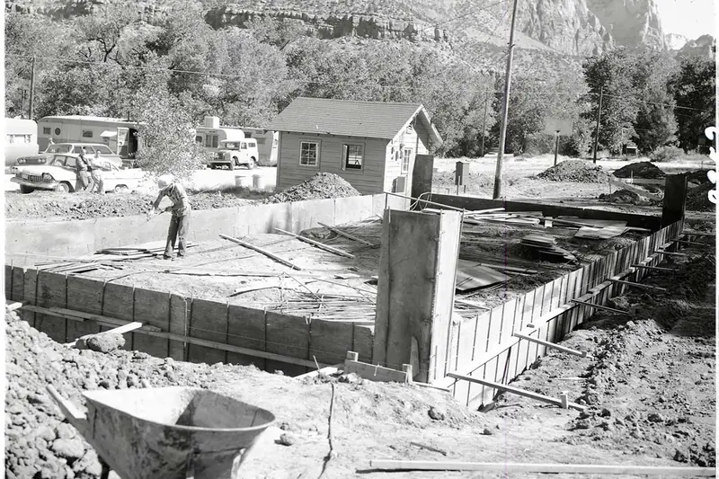 Black-and-white photo of 1950s workers setting wooden forms for a concrete house foundation