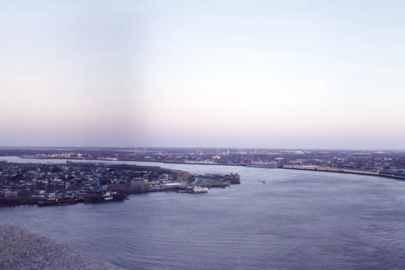 The Mississippi River curving past New Orleans at dusk, seen from high above with the city along both banks