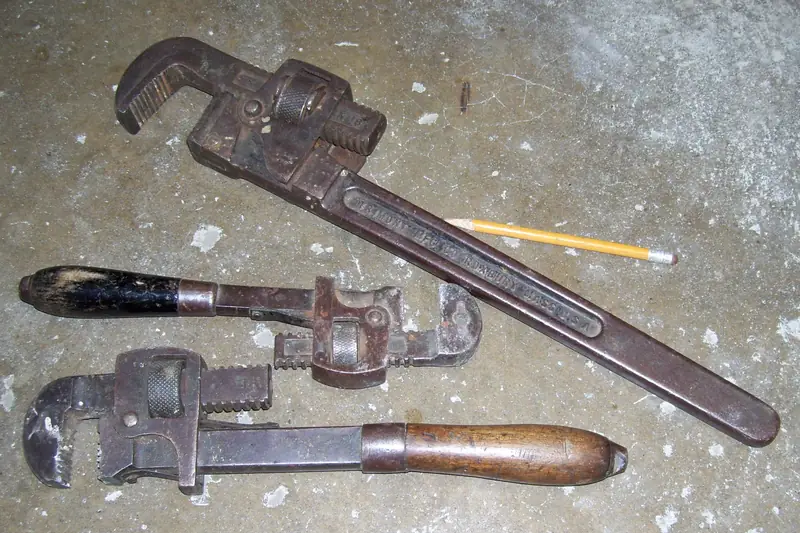 Three pipe wrenches lying on a concrete floor